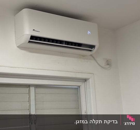 מזגן מותקן על קיר מעל חלון